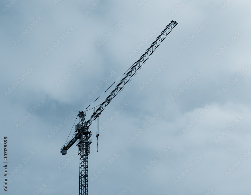 Tower crane on sky background. Blue toned.