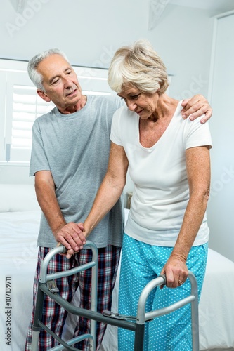 Canvas Print Aged woman with walker by man in bedroom