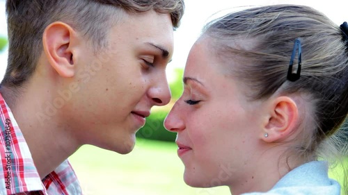 Young couple in love kissing in park closeup portrait