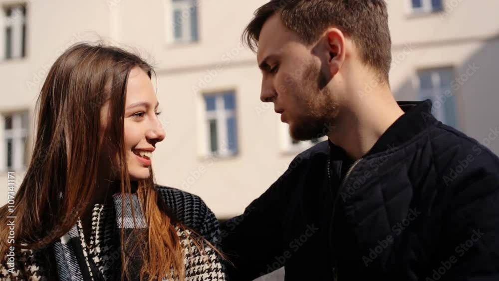 Two young lovers talking to each others while sitting on a bench at the street. Two young lovers talking to each others while sitting on a bench at the street.