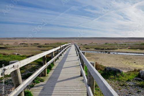 wooden bridge over the creek flowing to Fleet Lagoon in the dunes of Chesil Beach Weymouth, Dorset, England