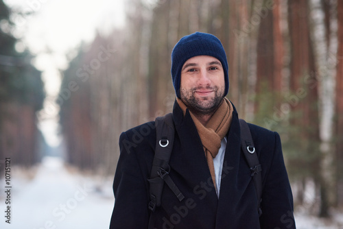 Positve man wearing coat in winter forest with snow