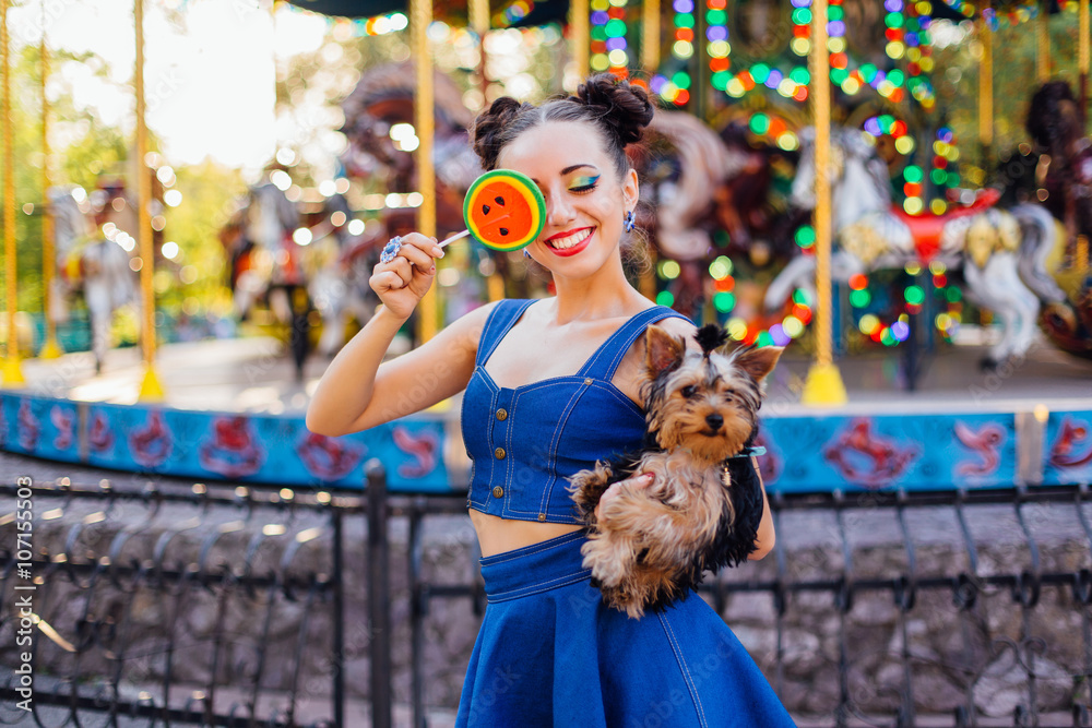 Bright makeup beautiful girl with Yorkshire Terrier holding watermelon lollipop.