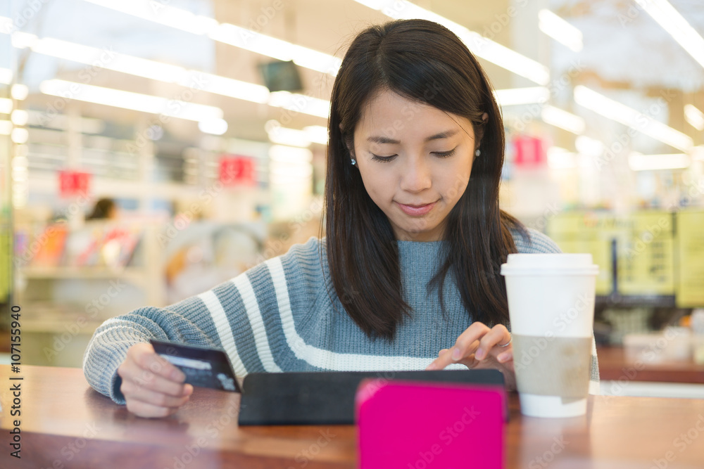 Woman using credit card for paying on tablet pc Woman using credit card for paying on tablet pc