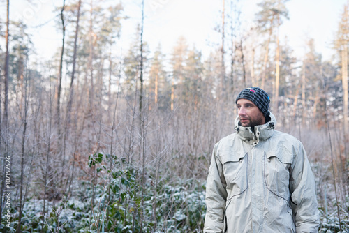 Young man dressed warm in winter forest with frost