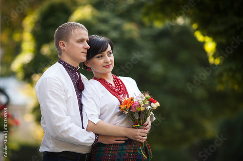  happy couple in national costumes on the background green park photo