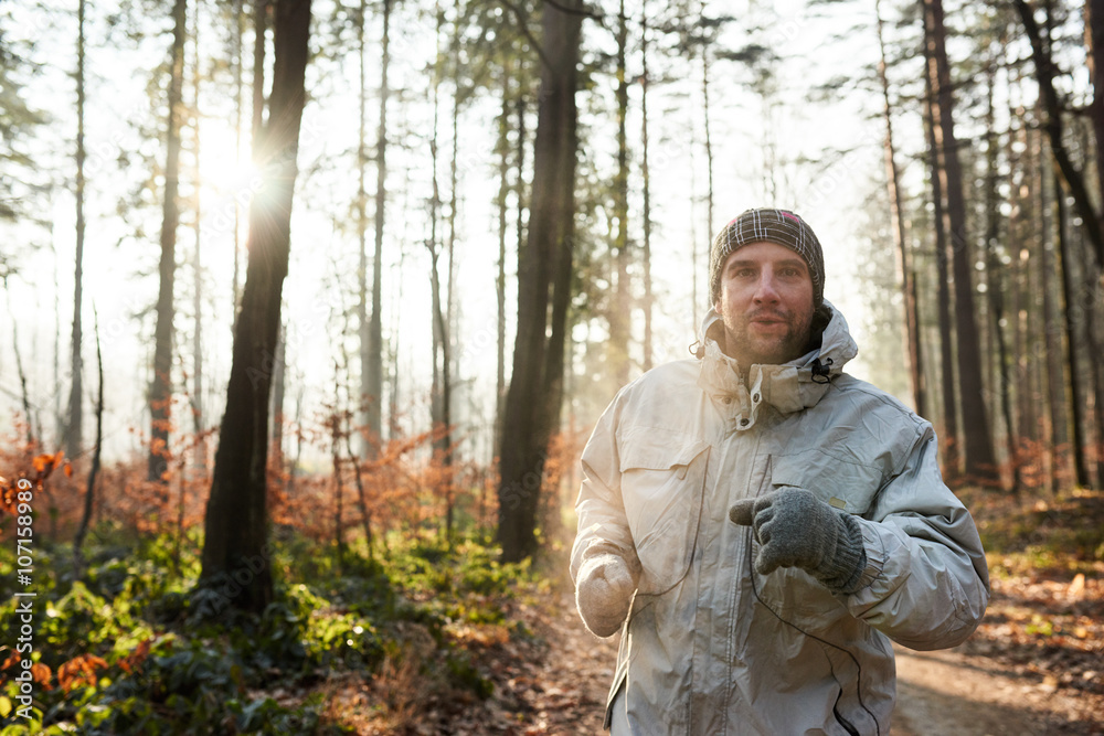 Man jogging in sunlit forest on a cold winter morning