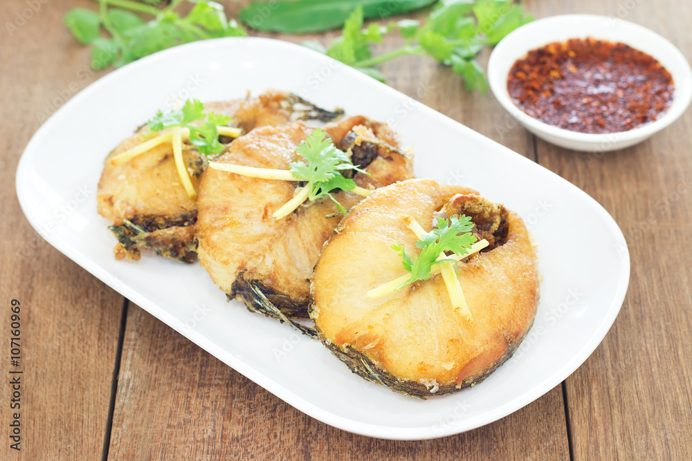Fried fish with chili sauce on a white plate, Wooden background Fried fish with chili sauce on a white plate, Wooden background