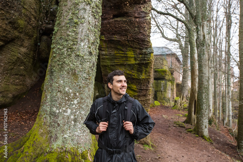 Young Man,Student hiking in forest.Man hiker smiling happy portrait looking up enjoying nature on foggy day during a trekking trip. Back of a young man outdoors in nature on a hiker path in forest.
