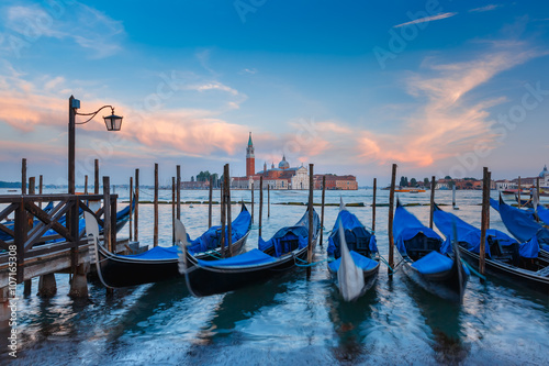Gondolas moored by Saint Mark square with San Giorgio di Maggiore church in the background in the evening, Venice, Italia © Kavalenkava