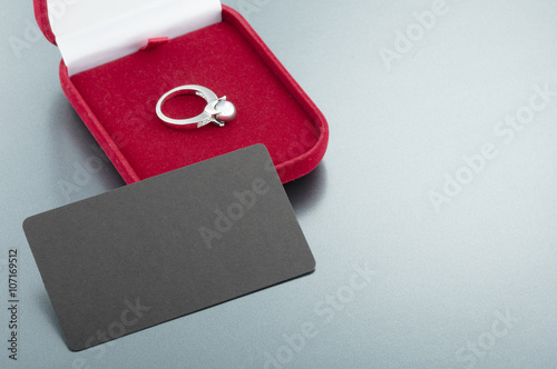 Image of wedding ring in a red gift box on gray background