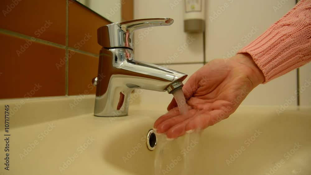 Female hand open mixer with water in bathroom Female hand open mixer with water in bathroom