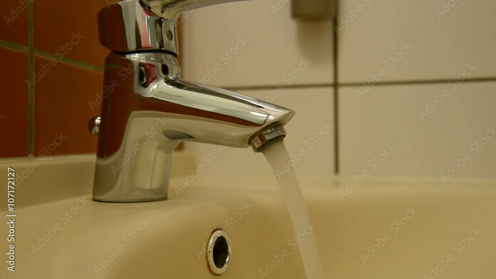 Female hand opens water tap and try water temperature Female hand opens water tap and try water temperature