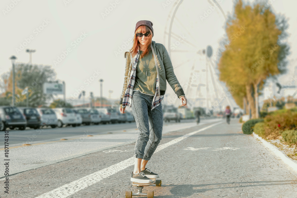 pretty girl on skate board in action - modern urban hipster girl in  fashionable clothes and skateboarding