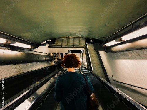 Young red head woman on escalator in a subway. 