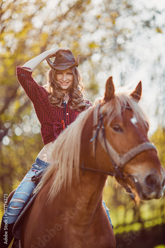 Beautiful smiling girl riding horse on autumn field
