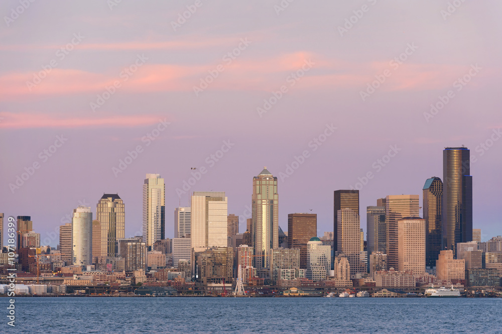 Naklejka premium Seattle Skyline at Sunset. During a beautiful Seattle, Washington sunset ferry boats run between Bainbridge Island and downtown Seattle. Modern skyscrapers line the waterfront.