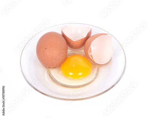 Cracked brown eggs on plate separated on white background
