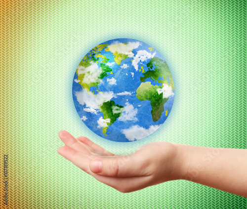 Fototapeta Naklejka Na Ścianę i Meble -  Woman holding globe on her hand on abstract green background