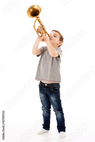 young boy blowing into a trumpet against white background