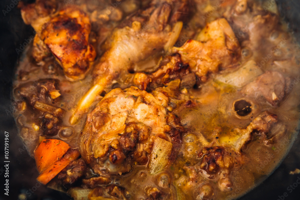 chicken in sauce with carrots on a pan closeup