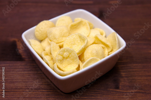 Potato snacks on a square bowl on wooden table