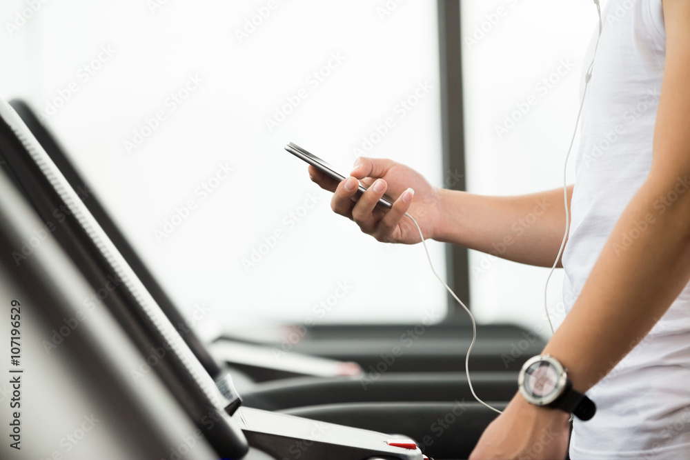 young handsome asian man using smartphone in modern gym young handsome asian man using smartphone in modern gym