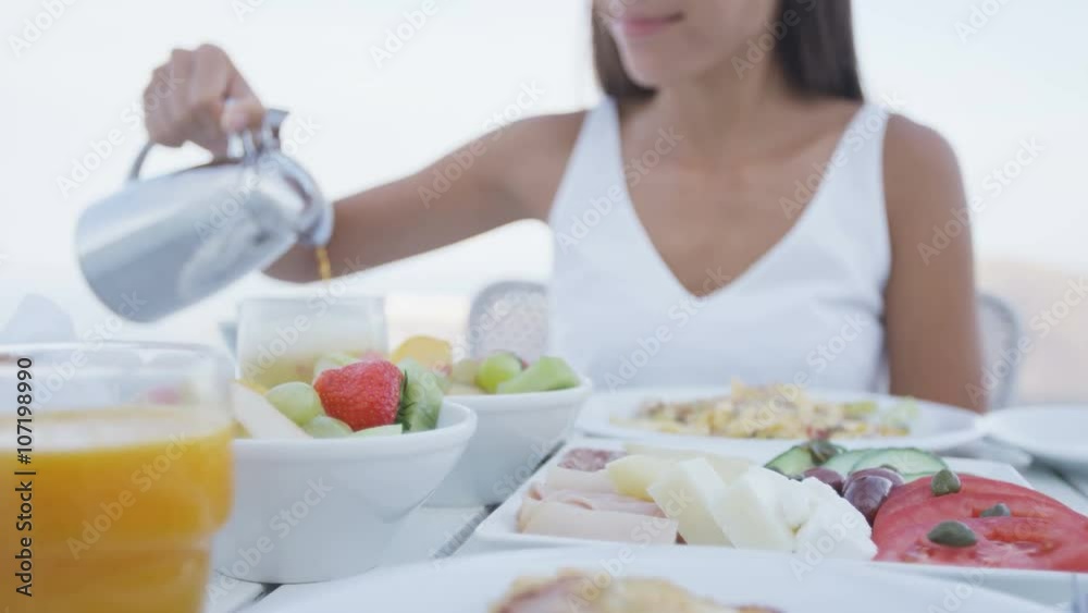 Young woman pouring coffee into cup. Variety of healthy food is served on terrace resort. Female is having delicious breakfast on vacation. Young woman pouring coffee into cup. Variety of healthy food is served on terrace resort. Female is having delicious breakfast on vacation.