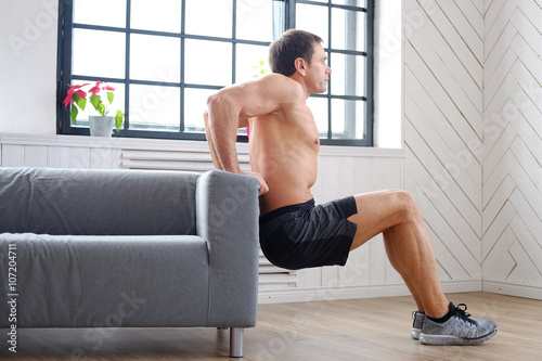 Shirtless man doing triceps workouts.