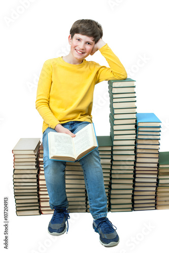 Obraz w ramie Young boy sitting on stacks of books and reading