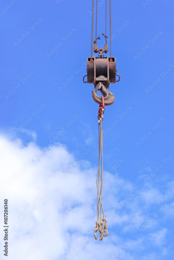 Metal crane hook  against the background of the blue sky with the clouds