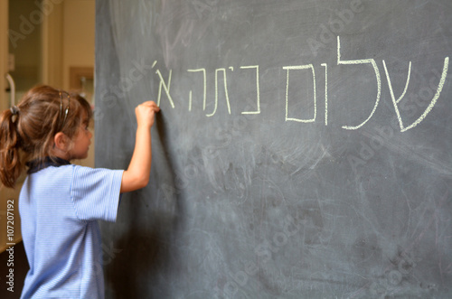Φωτογραφία Little girl writes Hello First Grade greetings in Hebrew