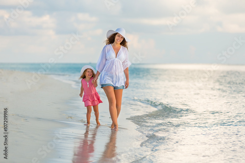 Mother and little daughter walking on the beach