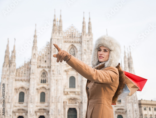 Woman with shopping bags pointing on copy space near Duomo © Alliance