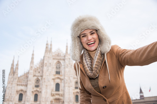 Happy woman tourist taking selfie in the front of Duomo, Milan
