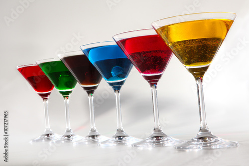 Group of glasses with colored beverages on white background