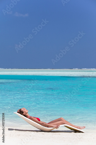 femme qui bronze sur une plage de sable blanc paradisiaque
