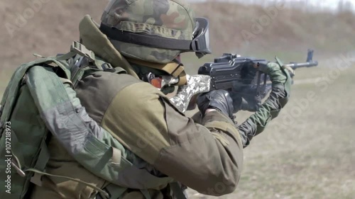 A soldier with a machine gun on a military firing range shooting at a target.