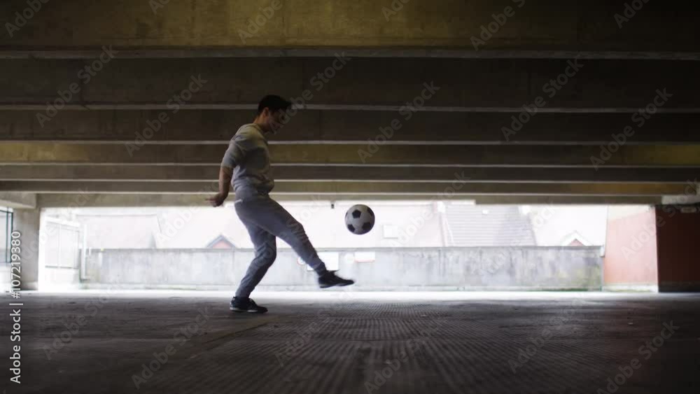 Football player doing kick up tricks in an urban city environment Football player doing kick up tricks in an urban city environment