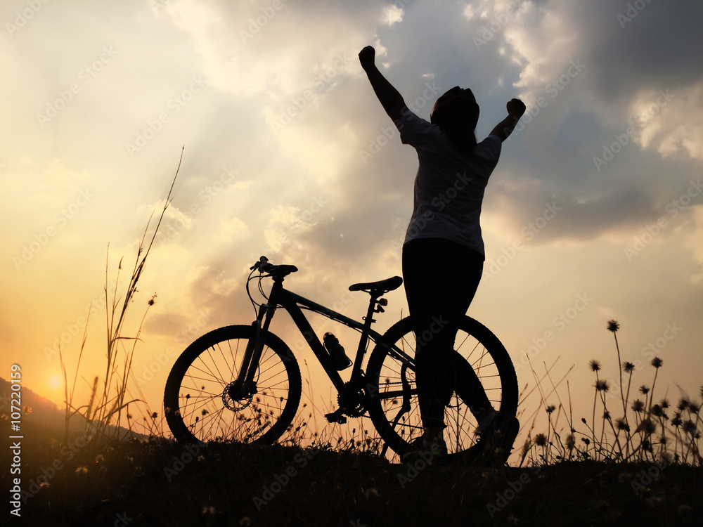 Obraz premium Silhouette women showing her hands with bicycle at sunset