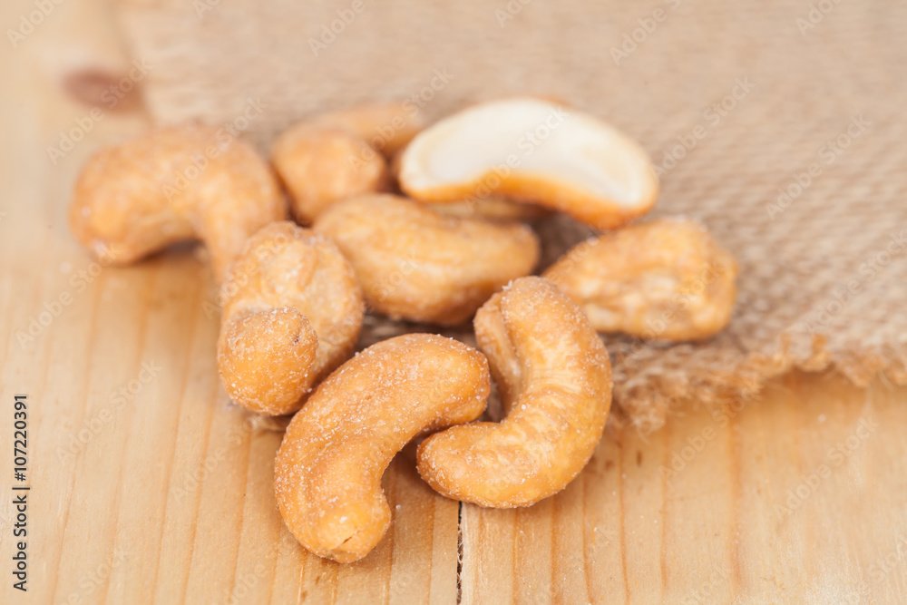 Pile of roasted cashew nuts on wood background