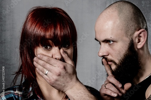 Strong bearded man covering woman face