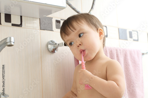 Baby child brushing teeth in bathroom photo