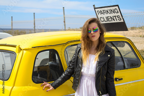 Young Hippie girl standing next to an old vintage, retro car photo