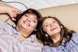 Mother and daughter listening to music in bed.