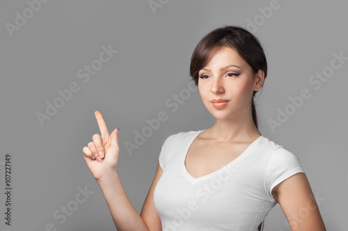 Beautiful young woman pointing her finger blank space