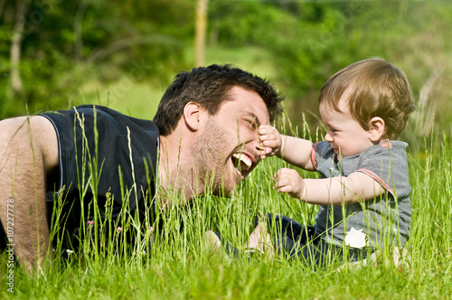 cute little child playing and joking in countryside with dad during summer