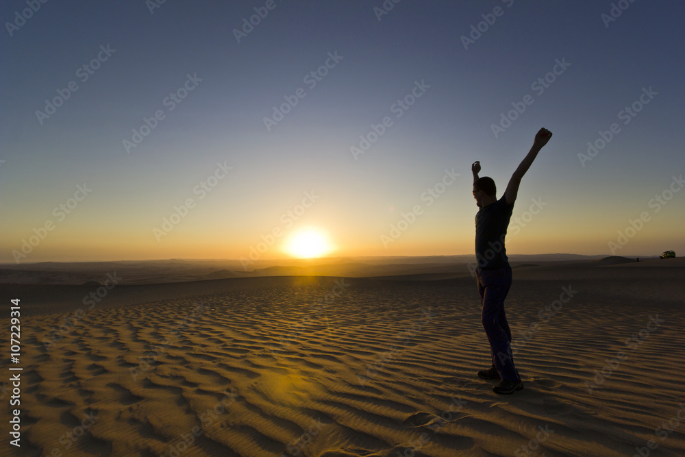 standing man with hands up at sunset in desert