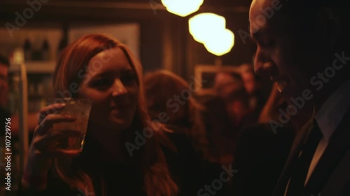 Young man and woman with drinks talking at a bar, close up