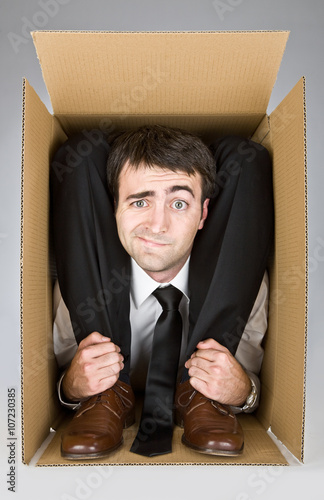flexible businessman with doubtful face in a cardboard box